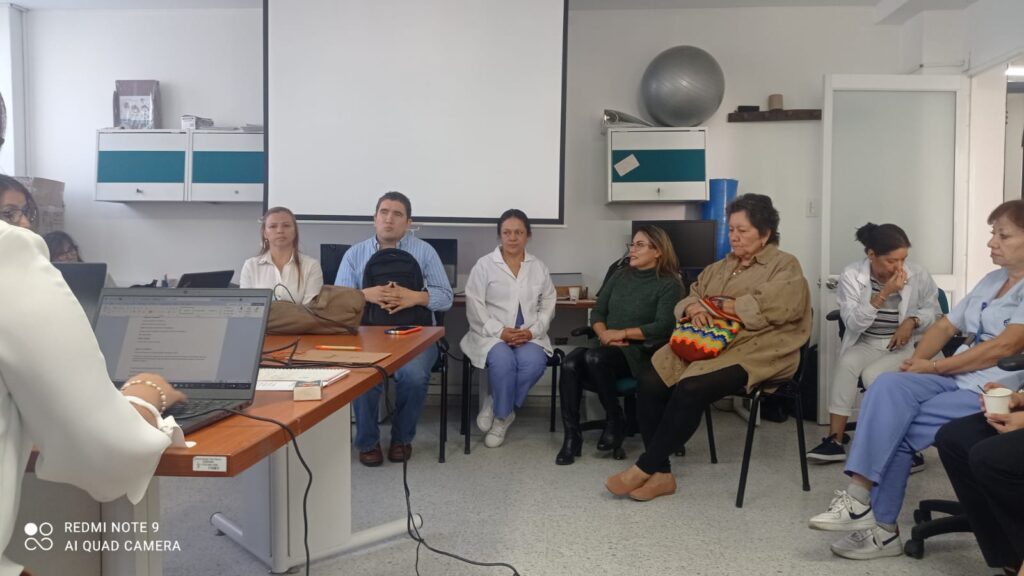 En la imagen un grupo de personas, representantes de la Fundación Santiago Luna, sentados en encuentro con representantes del Departamento de Fonoaudiología de la Univalle en una reunión en una sala de encuentros