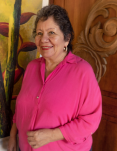 Fotografía de la señora Azucena Hernández Ángel, quien viste una blusa fucsia, su rostro muestra un gesto amable con una gran sonrisa.